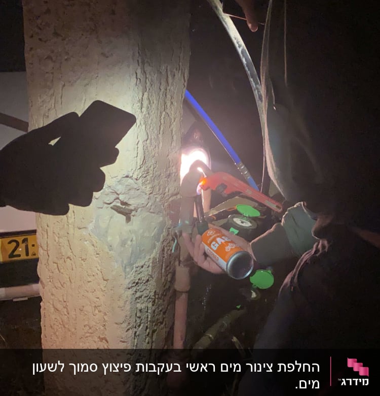 אדם עובד עם מפתח צינורות ופנס על צינור